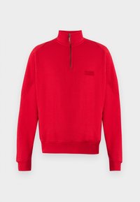Sudadera roja de punto con cuello de media cremallera, puños y bajo acanalados. Presenta un logo en negro en el lado izquierdo. Fabricada con tejido suave.