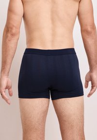 Bóxer de color azul marino hecho de tela elástica, con una cintura de elastano suave y un diseño ajustado, costuras visibles y un patrón minimalista.