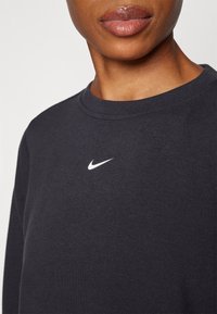 Sweat-shirt bleu marine en mélange de coton, avec un col rond, des manches longues et un petit logo Nike blanc sur la poitrine. Texture lisse.