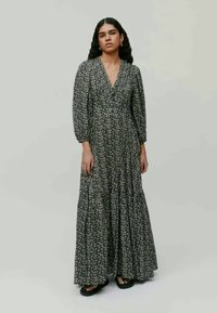 Μαύρο μακρύ φόρεμα με floral σχέδιο, v-λαιμόκοψη και μανίκια puff. Η φούστα με στρώσεις διαθέτει κροσέ και είναι κατασκευασμένη από ελαφρύ ύφασμα.