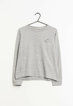 Sweat-shirt gris clair à manches longues sur un cintre noir avec un petit dessin en ligne noire d'oiseaux et le texte "fly away" en haut à gauche de la poitrine.