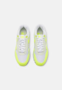 Pantofi sport cu un superior din plasă albă și sintetică, accentuați cu detalii de un galben neon, șireturi albe plate și guler căptușit.
