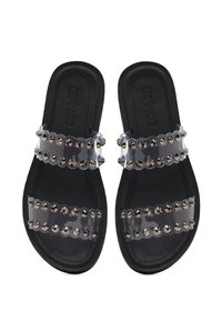Sandales noires à glissière avec deux sangles transparentes, chacune ornée de clous en argent. Semelle plate au design lisse et logo à l'intérieur.