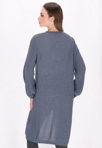 Grå långärmad cardigan med strukturerad stickning, öppen front och avslappnad passform. Funktioner ribbstickade ärmar och nederkant, knä-lång design.