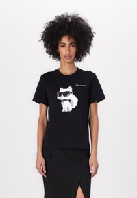 Tricou negru cu un grafic de pisică albă purtând ochelari de soare, mâneci scurte, guler rotund și un logo în partea stângă sus.
