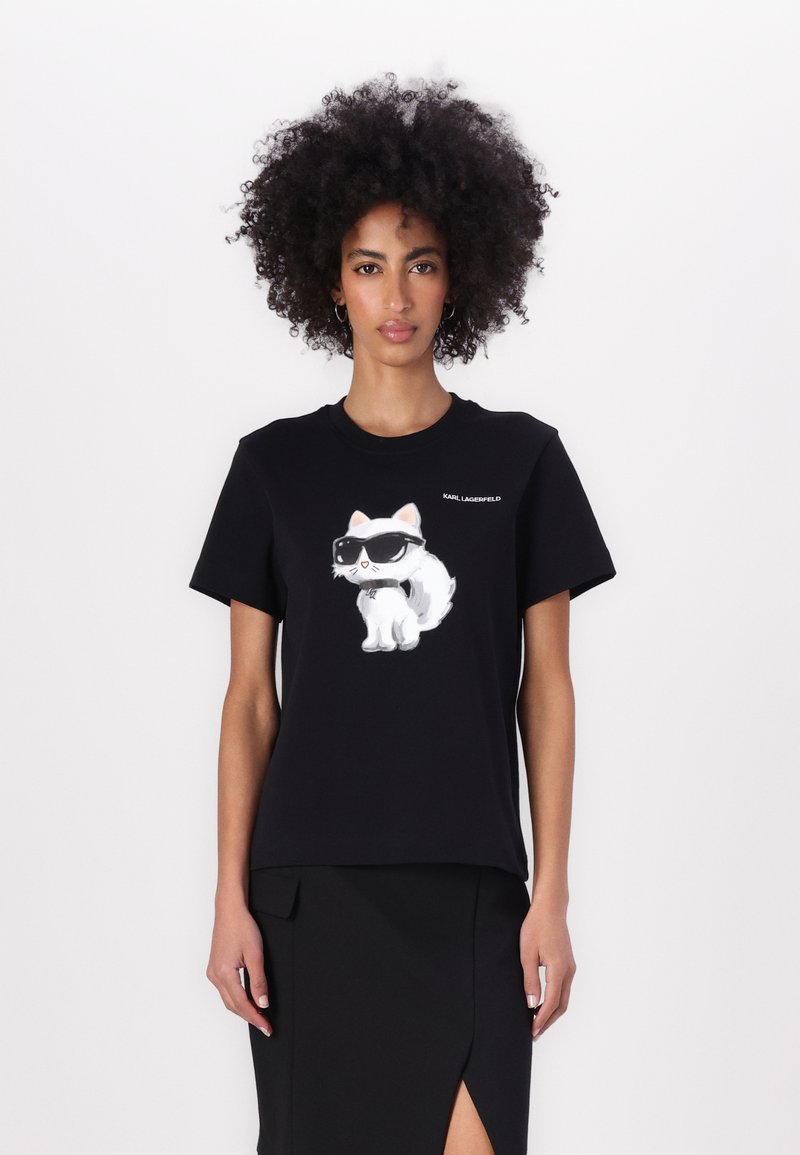 Tricou negru cu un grafic de pisică albă purtând ochelari de soare, mâneci scurte, guler rotund și un logo în partea stângă sus.