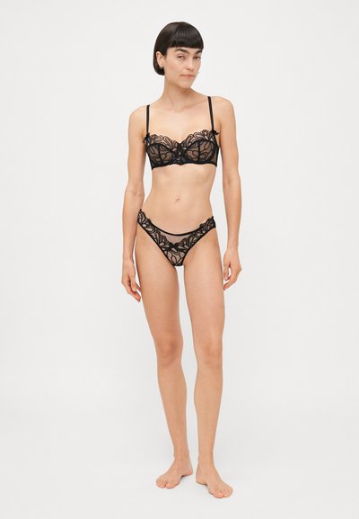 Ensemble de lingerie en dentelle noire comprenant un soutien-gorge avec broderie florale et bretelles réglables, associé à des culottes taille haute assorties.