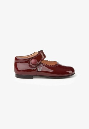 Zapato Mary Jane de charol burdeos con borde ondulado, correa ajustable con botón redondo y suela plana. Textura suave, diseño clásico.