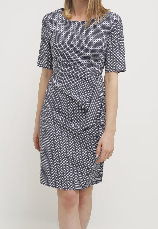 Robe portefeuille bleu marine avec motif géométrique blanc, manches courtes, et détail noué sur le côté. Tissu lisse avec une silhouette ajustée.