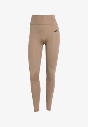 Leggings de talle alto en color beige, hechos de una tela elástica, que presentan una silueta ajustada y un acento de logo negro en la cadera izquierda.