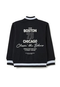 Felpa nera con testo bianco. Presenta un colletto e dei polsini a righe. Il design sul retro include nomi di città, numeri e grafiche in tema motociclistico.