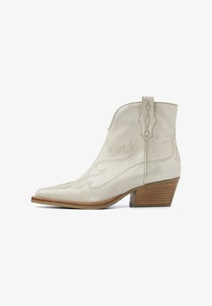 Cream textured leather ankle boot with pointed toe, subtle western stitching, and a stacked wooden heel. Features a pull tab for easy wear.