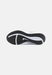 White athletic shoe sole with a textured black rubber grip. Features a central groove and a distinct Nike logo in white.