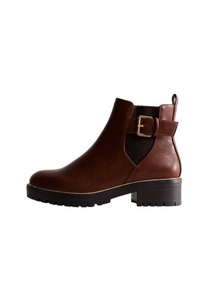 Bottine en cuir marron avec panneaux latéraux élastiques, détail boucle et accents noirs texturés. Dispose d'une semelle noire robuste et d'un talon carré.