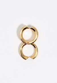 Pendiente clip de tono dorado, circular, con un acabado liso y brillante. Dos arcos unidos crean un diseño interconectado con un pequeño acento de unión.