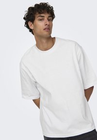 Witte oversized katoenen t-shirt met een ronde halslijn, korte mouwen en een relaxte pasvorm. Geen zichtbare patronen of accenten.