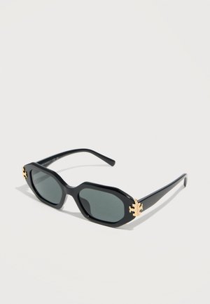 Gafas de sol negras octagonales con lentes oscuras y detalles de logo dorado en las bisagras, exhibidas sobre una superficie clara.