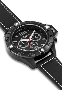 Reloj analógico negro con un dial negro texturizado, acentos plateados y una manecilla de segundos roja. Presenta una correa de cuero negra con costuras blancas.