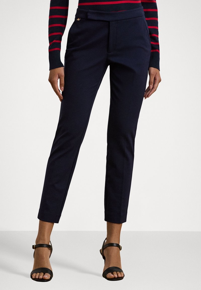 Marinblå skräddarsydda byxor med slim fit, som har en mjuk textur och en subtil gul accent på midjebandet. Kombineras med svarta remsandaler.