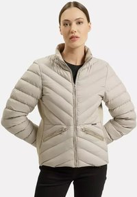 Jasno beżowa kurtka puchowa z wzorem w kształcie chevronu, wysokim kołnierzem i dwiema kieszeniami na zamek. Charakteryzuje się gładką fakturą i dopasowanym krojem.
