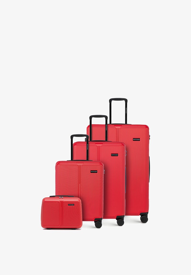 Quatre valises rigides rouges de tailles variées avec des poignées extensibles noires et des roues, disposées en ordre croissant de l'avant vers l'arrière.