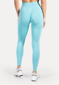 Leggings de cintura alta y ajustados en un color turquesa claro. Hechos de un material liso y elástico con detalles texturizados a lo largo de las costuras.