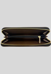 Portafoglio zip-around in pelle nera aperto per mostrare diversi scomparti per carte e un comparto centrale con zip per le monete, dotato di un tirante dorato.