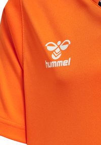 Orange t-shirt med korte ærmer lavet af glat, let stof. Har et hvidt logo af en bi og brandnavnet "hummel."