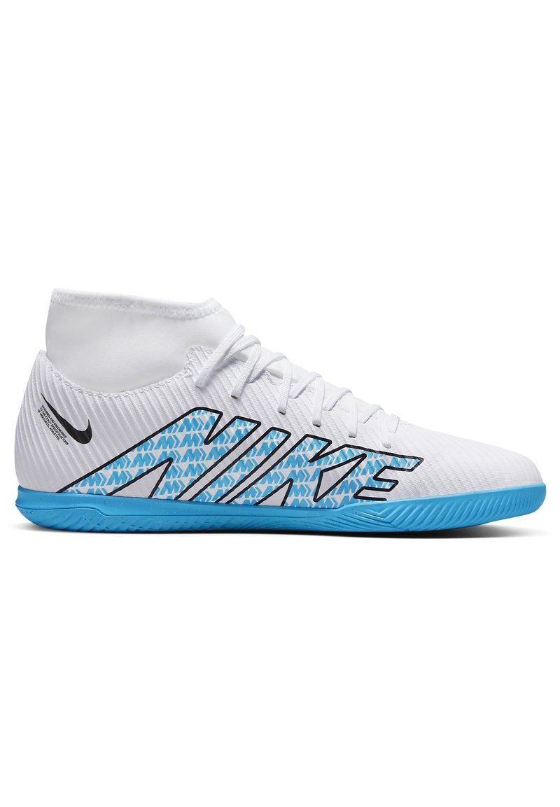 Valkoiset korkeavyötäröiset urheilukengät, joissa on teksturoitu päällinen, siniset korostukset, musta Nike-logo ja uritettu pohja pitoa varten.