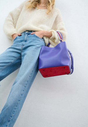Fialová kožená taška s červeným semišovým dnem, která má pevný tvar, nastavitelný popruh a dekorativní kovové doplňky.