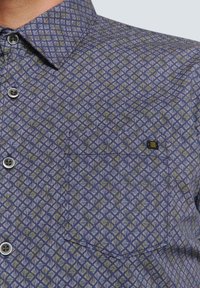 Korte mouwen overhemd in marineblauw met een geometrisch bladerenpatroon in lichtblauw en groen. Voorzien van een button-down kraag en een borstzak.