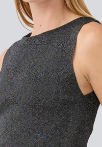 Sleeveless black top with a shimmering metallic texture, featuring a high neckline and cutout details at the shoulders.