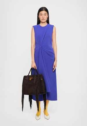 Abito senza maniche di un blu reale con dettagli plissettati; borsa in suede marrone scuro con frange; collant gialli; scarpe con tacco bianche.