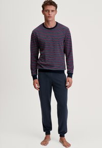 Chemise à rayures navy à manches longues avec des rayures rouges, bleues et blanches, associée à un pantalon de jogging court gris foncé, doté de poignets élastiques.