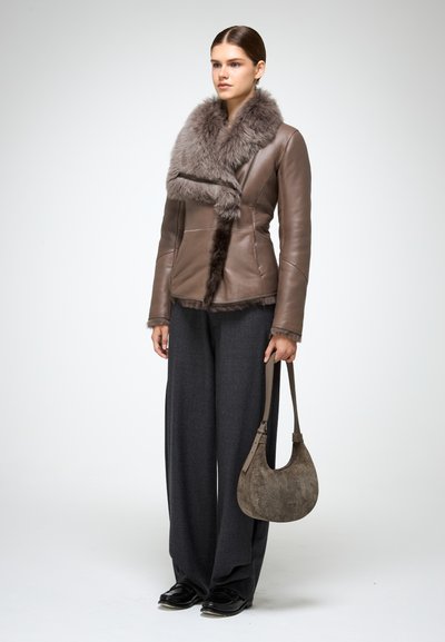 Giacca di pelle marrone con colletto e rifiniture in pelliccia grigia. Abbinata a pantaloni larghi scuri e una borsa a spalla in suede marrone. Scarpe nere.