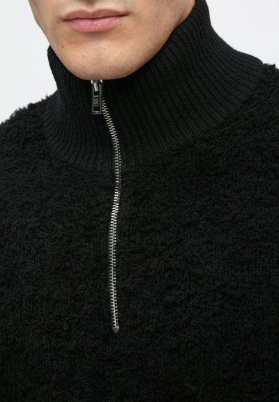 Schwarzer Pullover mit engem Kragen aus strukturiertem Stoff und einem Reißverschluss vorne mit silbernem Reißverschluss. Weiche und gemütliche Optik.