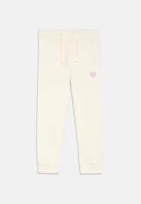 Cremfarbene Jogginghosen mit elastischem Bund, Zugband, Seitentaschen, gerippten Knöchelbündchen und einem kleinen rosa Herzen auf dem rechten Oberschenkel.