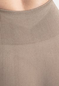 Ceinture élastique beige avec un côtelé texturé et un tissu lisse, présentant un motif triangulaire près de la taille. Design doux et ajusté.