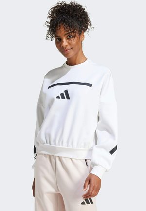 Witte sweatshirt met zwarte streep en logo, geribbelde manchetten en tailleband. De stof lijkt zacht en textuur te hebben. Gepaard met lichtroze broek.