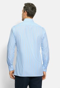 Camicia azzurro chiaro con strisce bianche verticali, maniche lunghe, polsini con bottoni e colletto strutturato. Tessuto con texture liscia.