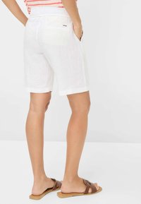 Pantaloni corti bianchi in lino con vestibilità comoda, dotati di tasche frontali, una tasca posteriore e un sottile accento del marchio sulla vita.