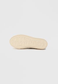 Potplat cipela od teksturirane, bež gumene tkanine s ponovljenim uzorkom logotipa "GUESS". Glatke ivice i fleksibilan dizajn.