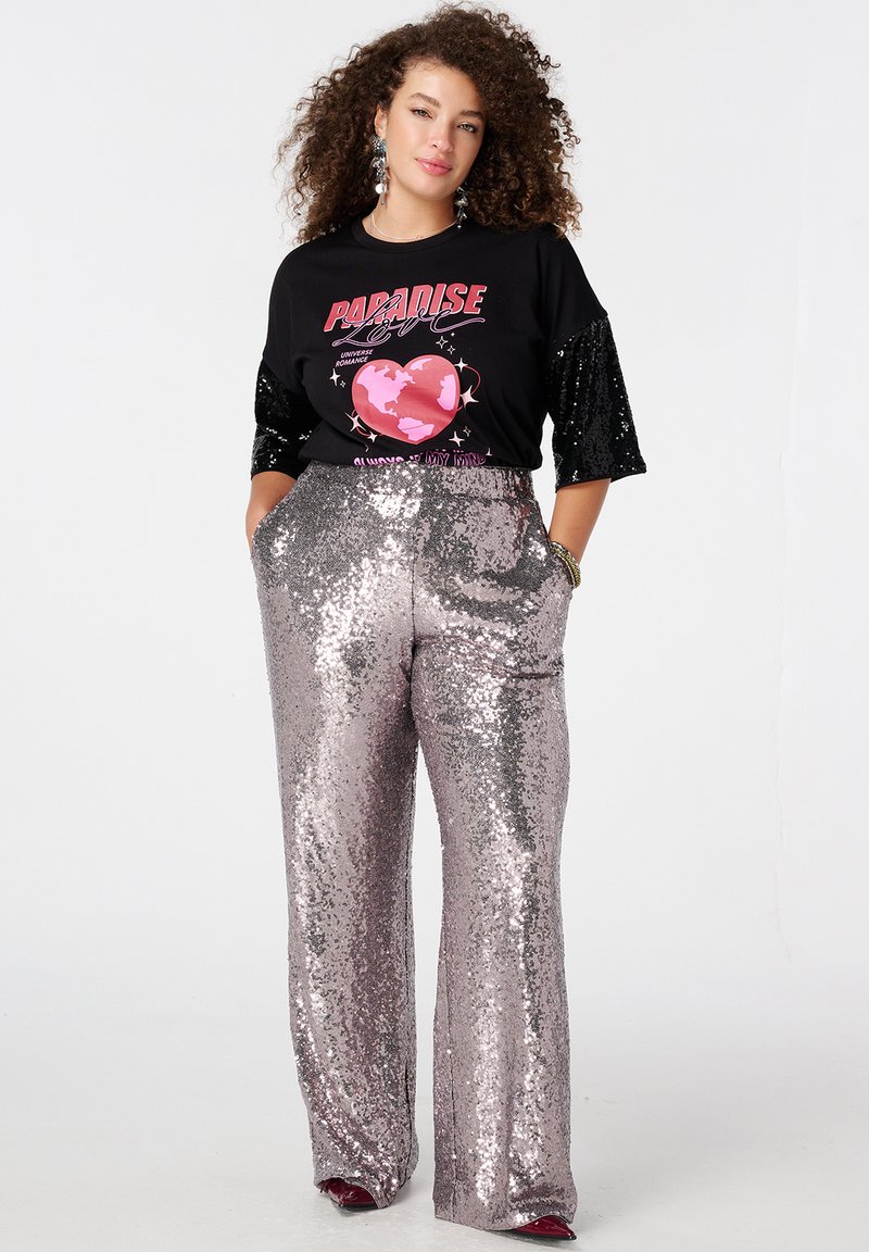 Zwart T-shirt met met pailletten versierde mouwen en een roze grafisch ontwerp; zilverkleurige, met pailletten bedekte broek met hoge taille en zakken; gladde textuur, wijde pijpen.