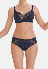Completo reggiseno e mutandine blu navy con pois, dettagli in pizzo e bordi scallop. Il reggiseno ha spalline regolabili e inserti in rete.
