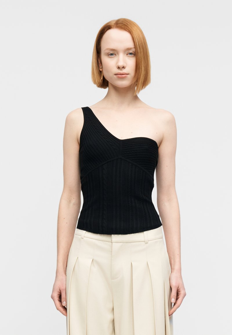 Haut noir côtelé à une épaule avec une coupe ajustée. Il présente des lignes de texture verticales et une silhouette structurée.