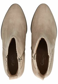 Botas de tobillo de ante beige con puntera puntiaguda, cremalleras laterales y una textura suave. Presenta un acento cosido a lo largo de la abertura.