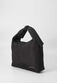 Svart nylon tote-veske med en knyttet håndtak, som har en glatt tekstur og merkevarenavnet "CASALL" trykt i hvitt.
