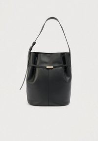 Μαύρη δερμάτινη τσάντα σε σχήμα κάδου με ρυθμιζόμενο ιμάντα ώμου και λεπτή οριζόντια ζώνη με πόμολο σε χρυσή απόχρωση στο μπροστινό μέρος.