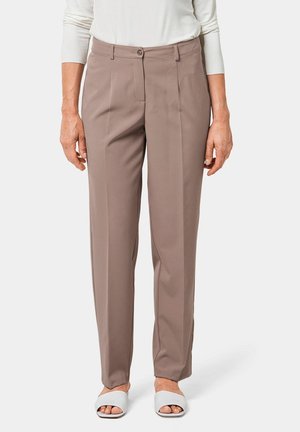 Beige op maat gemaakte broeken met een rechte pijp, knoopsluiting en voorplooien. Draagt met witte slide sandalen, die een gladde textuur tonen.