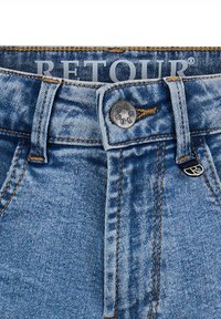 Jasnoniebieskie dżinsy z wysokim stanem, zamykane na srebrny metalowy guzik, z kontrastowymi pomarańczowymi szwami. Metka marki widoczna na górze.